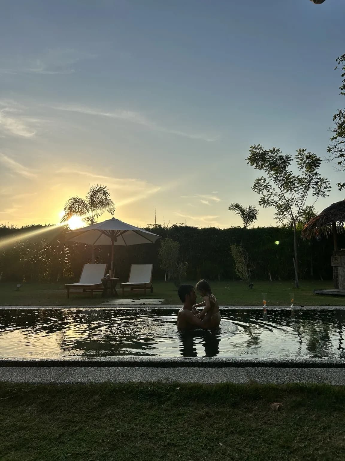 Rodinný okamžik v bazénu Temple Tree Resort při západu slunce