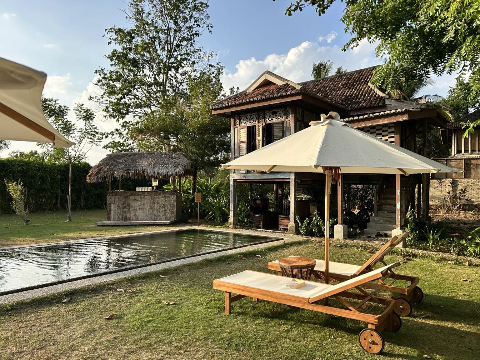 Historický dřevěný dům, bazén a lehátka v zahradě Temple Tree Resort Langkawi