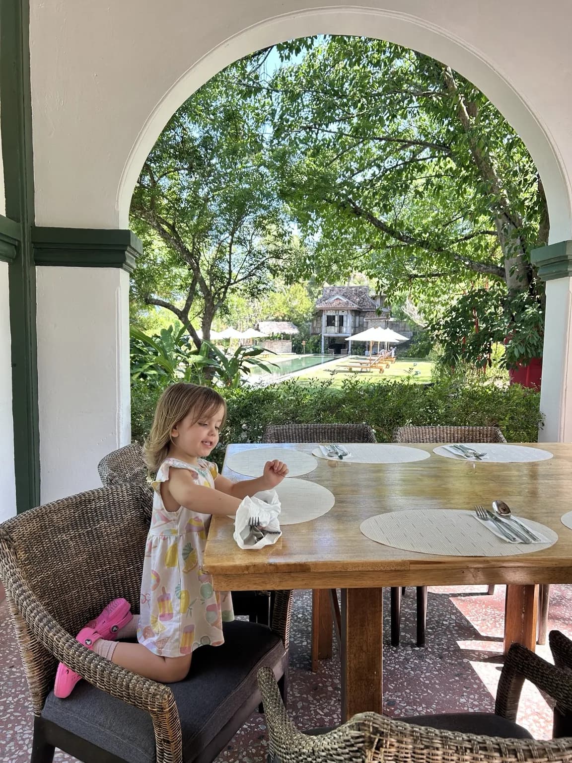 Dítě u jídelního stolu na verandě s výhledem na zahradu Temple Tree Resort