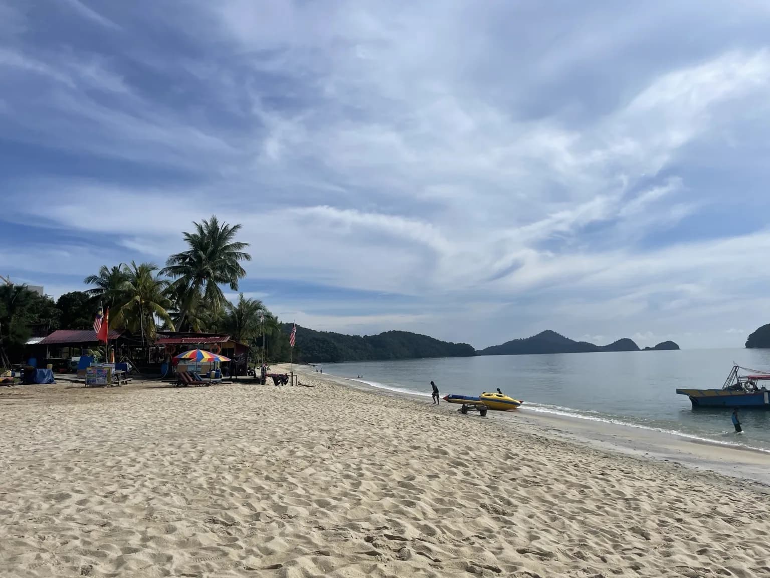 Široká písečná pláž na Langkawi s palmami a výhledem na malé ostrovy
