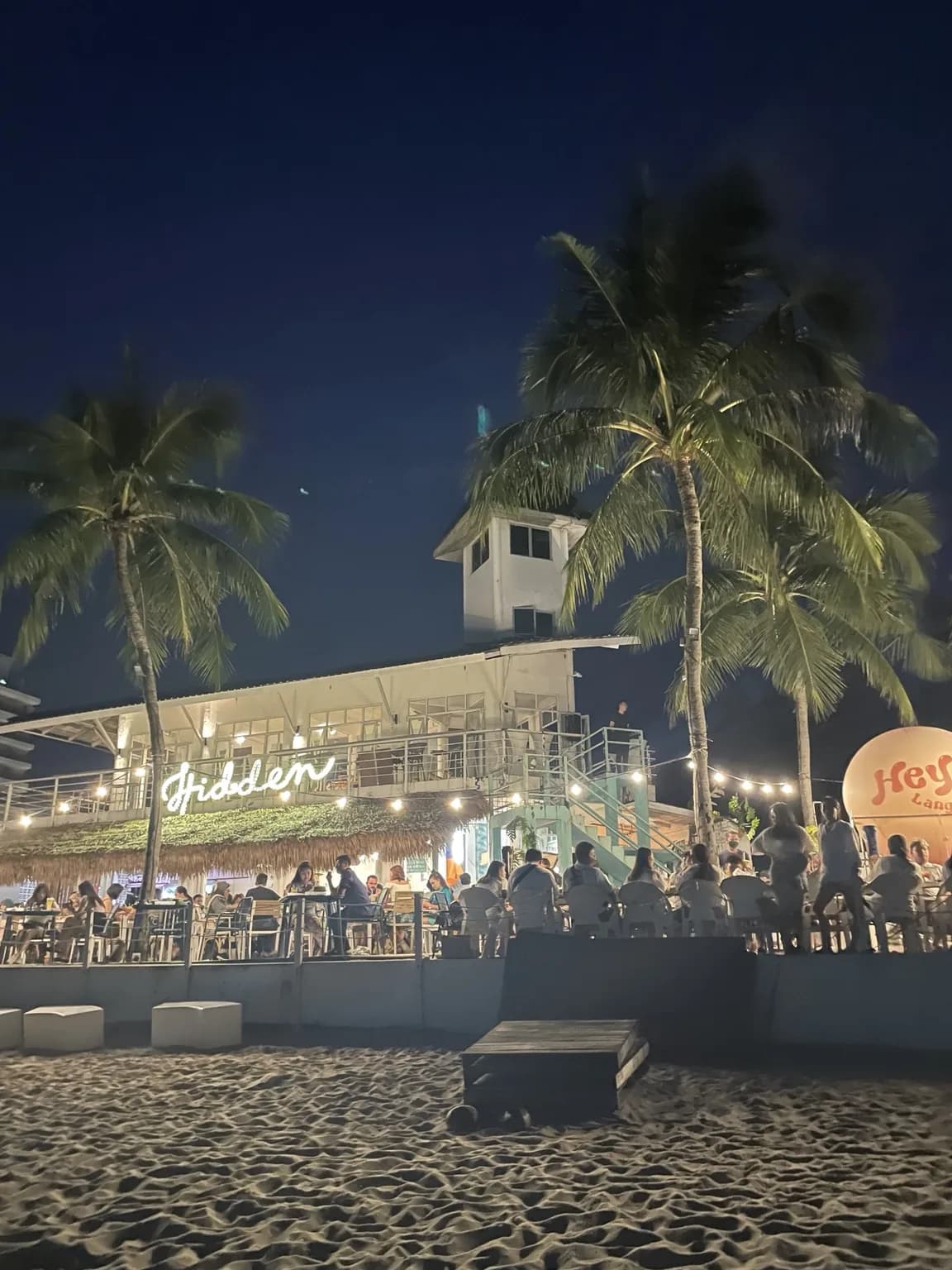 Nasvícená restaurace u pláže na Langkawi večer mezi palmami
