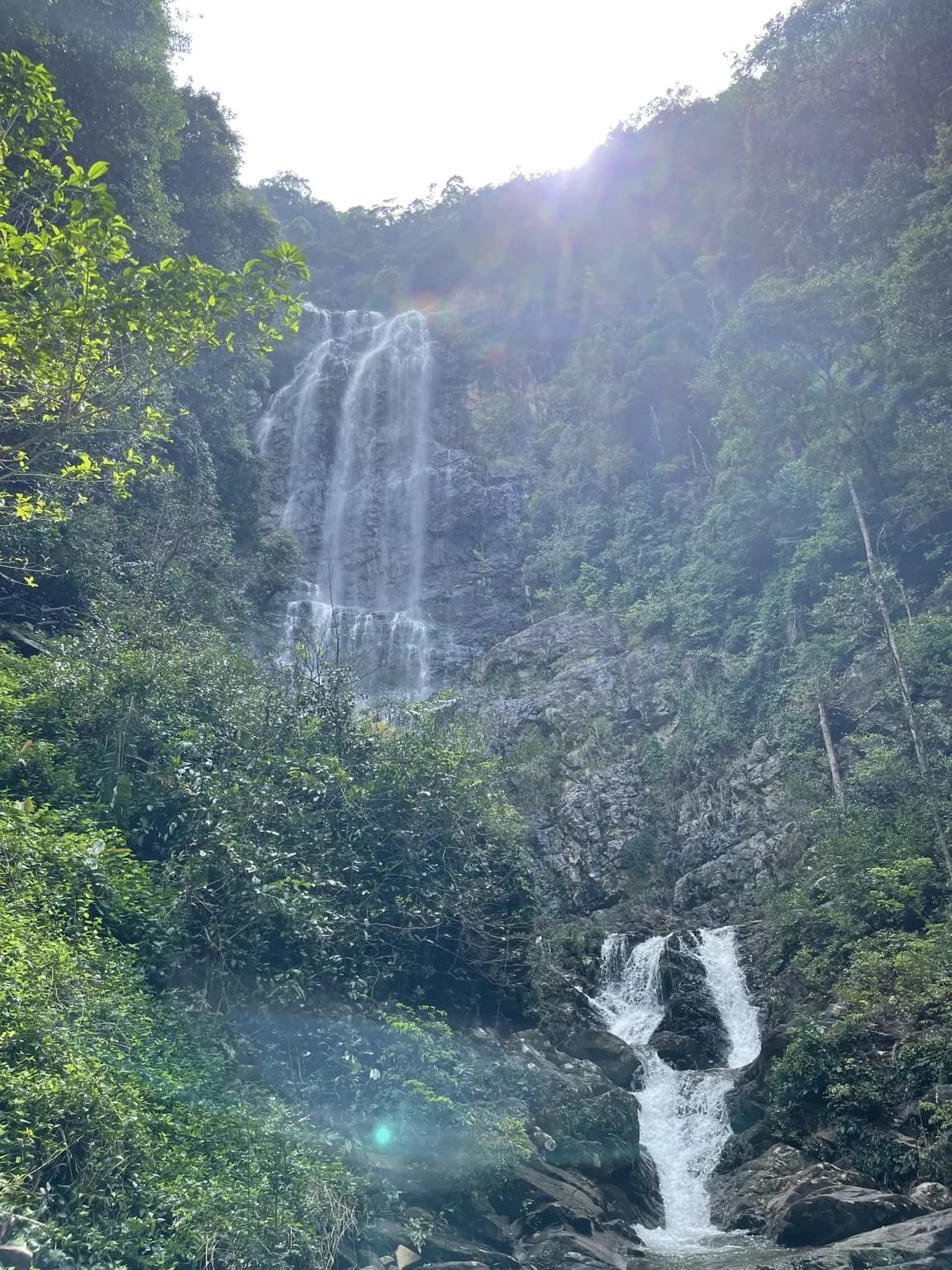 Vysoký vodopád padající mezi skalami a tropickou vegetací na Langkawi