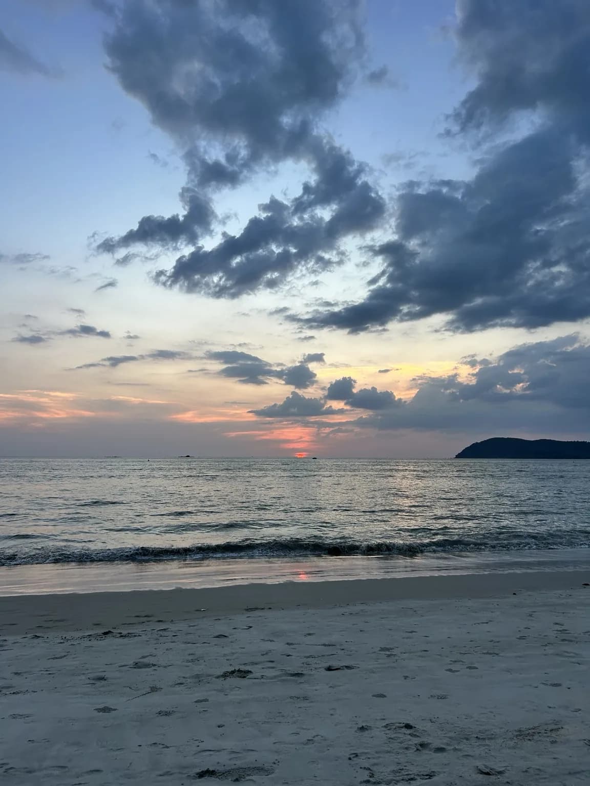 Oranžový západ slunce nad mořem a písečnou pláží na Langkawi