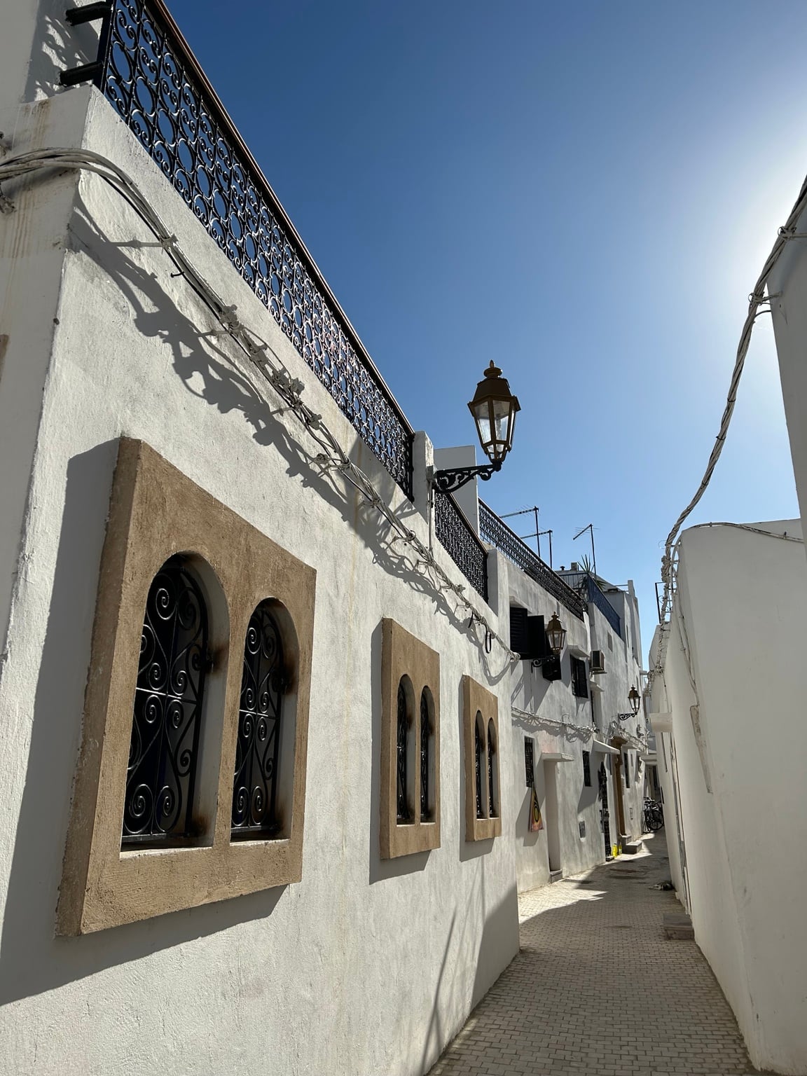 Bílá ulička v Kasbah des Oudayas s kovovými okny a lucernami