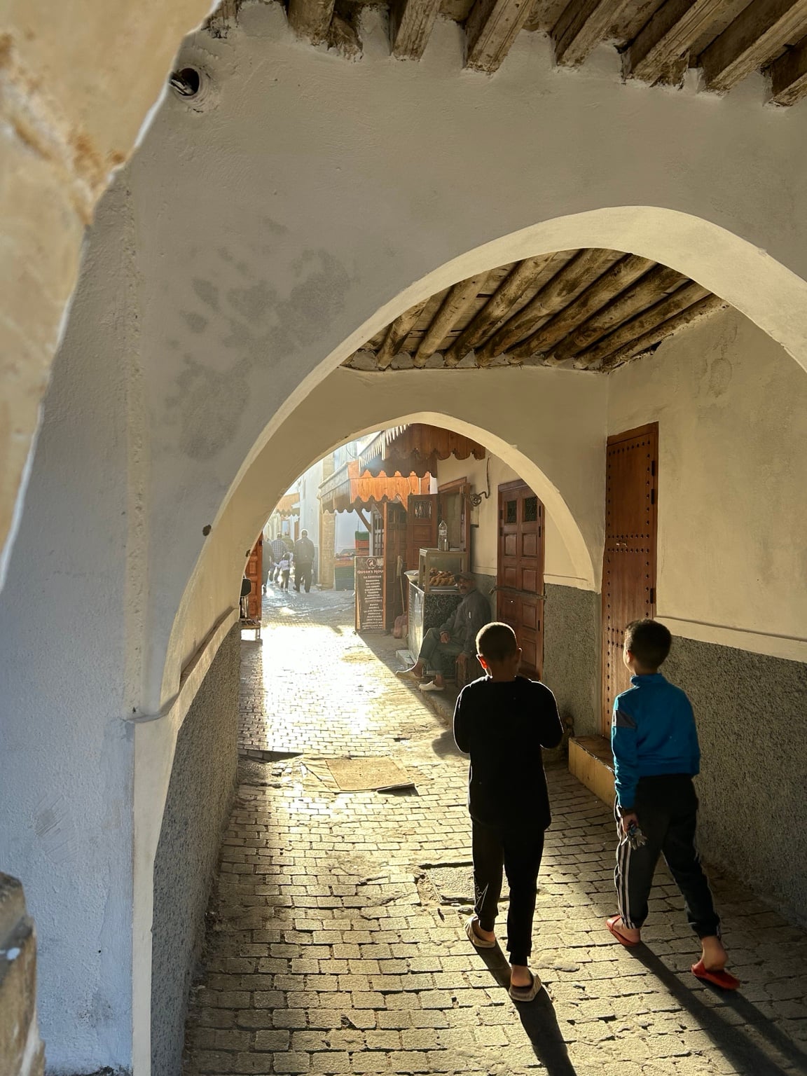Sluncem osvětlená ulička pod bílými oblouky rabatské mediny