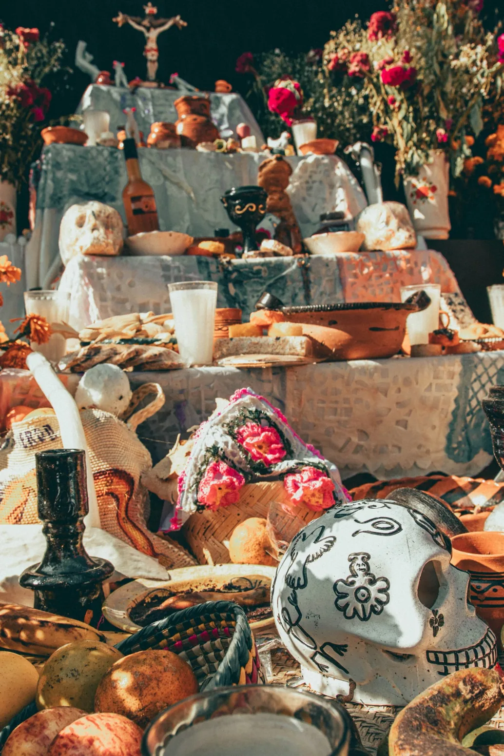 Detail mexické ofrendy s jídlem, keramikou, fotografiemi a ozdobami Día de Muertos
