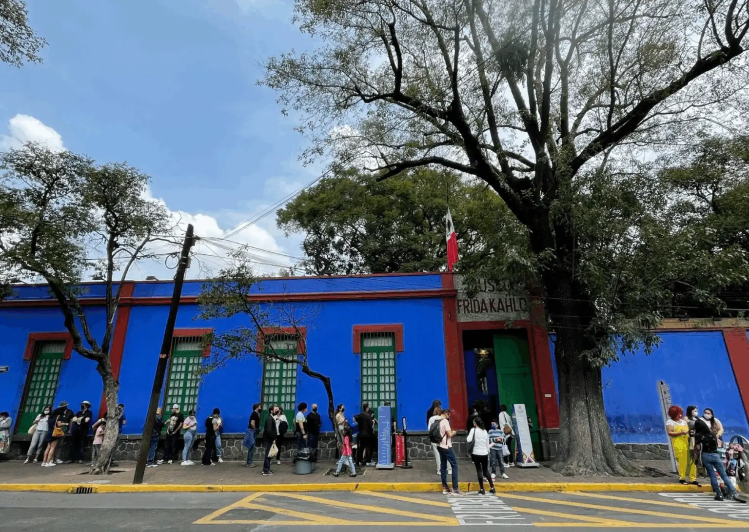 Co dělat v Mexico City - Casa Azul, dům Fridy Kahlo v Coyoacánu v Mexico City, s návštěvníky čekajícími ve frontě před modrou fasádou muzea.