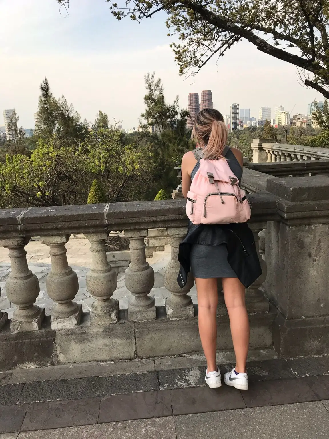 Cestovatelka s růžovým batohem obdivuje výhled na čtvrť Polanco z terasy Castillo de Chapultepec v Mexico City.