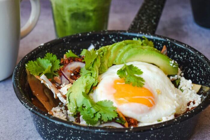 Tradiční mexické chilaquiles se zelenou a červenou salsou, smaženými tortillami, sýrem a vejcem.