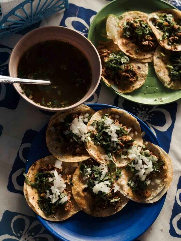 Stůl s mexickými tacos, miskami salsy a limetkami připravený k jídlu.