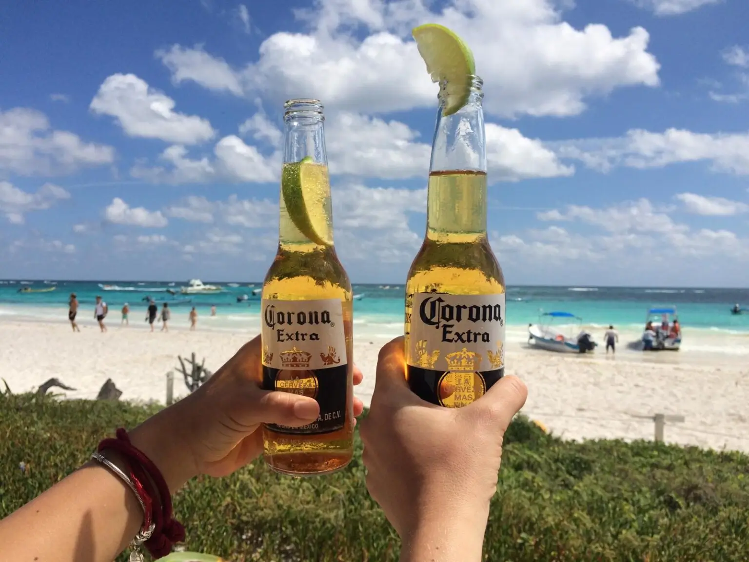 Dvě lahve piva corona na pláži s bílým pískem a tyrkysovým karibikem v mexickém Tulum
