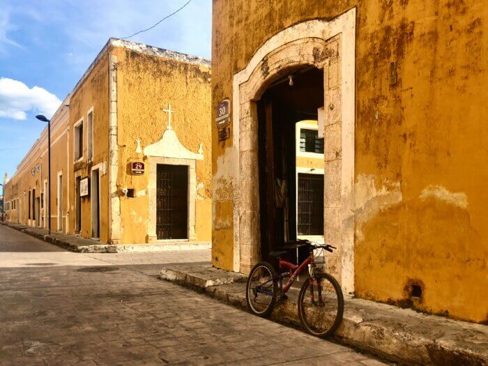 Ulice a žluté domy s opřeným kolem ve žlutém městě Izamal na poloostrově Yucatán v Mexiku.